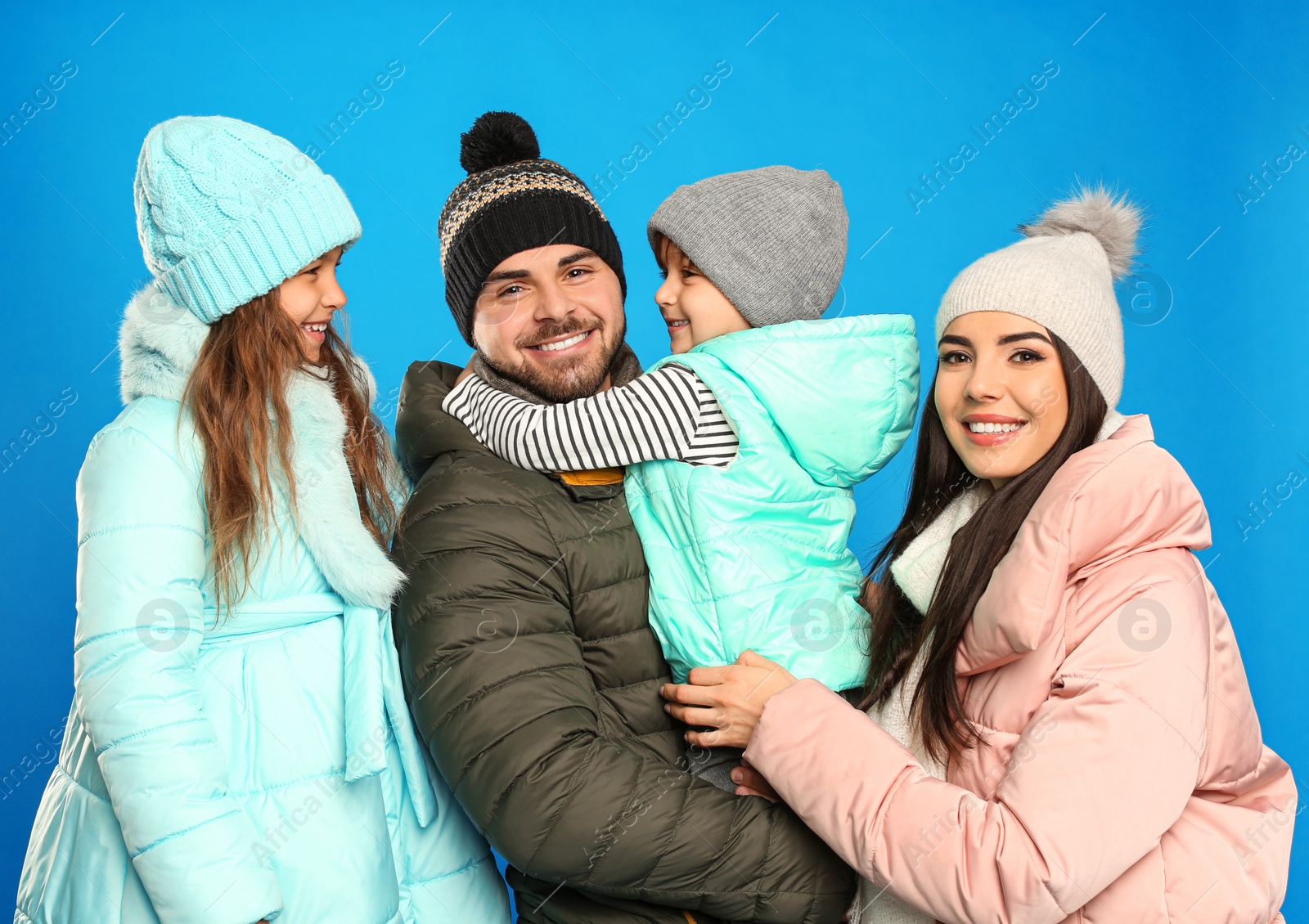 Photo of Happy family in warm clothes on blue background. Winter vacation