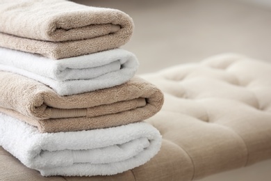 Stack of clean towels on bed end bench indoors