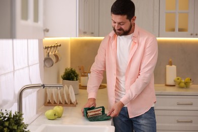 Man packing sandwich into beeswax food wrap at countertop in kitchen