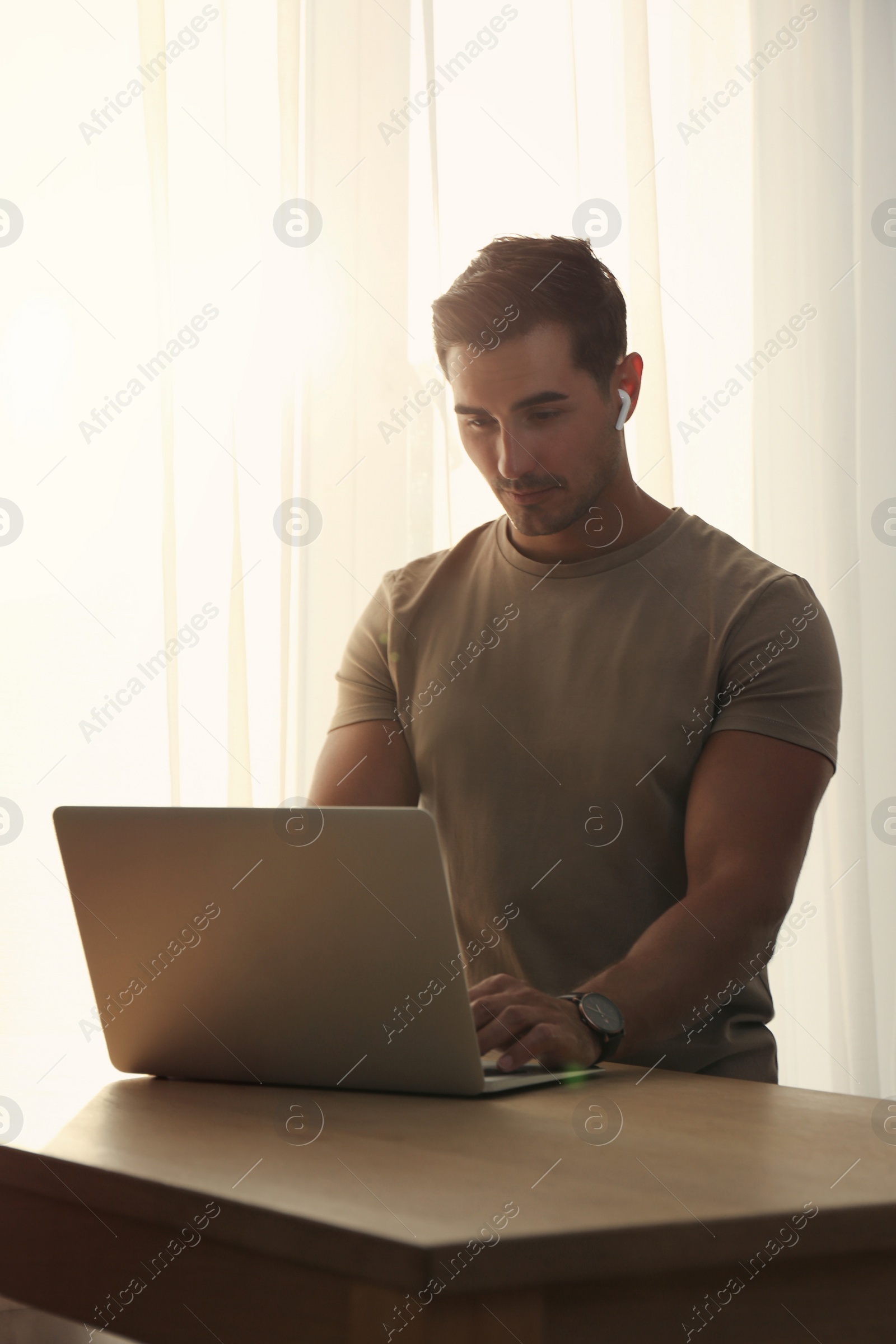 Photo of Portrait of young man with laptop at table indoors