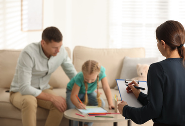 Photo of Child psychotherapist working with little girl and her father in office