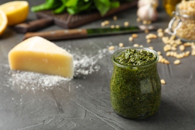 Photo of Jar with basil pesto sauce on table. Space for text