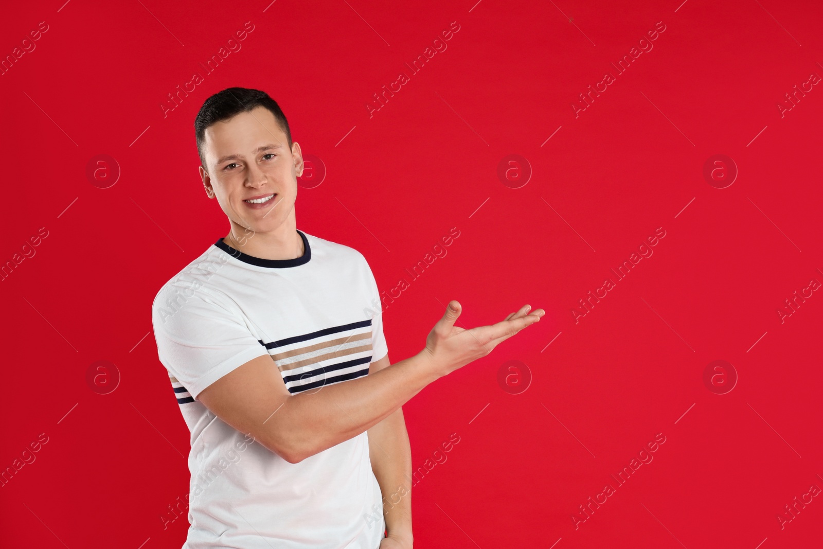 Photo of Happy handsome young man on red background. Space for text