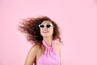 Photo of Portrait of laughing African-American woman with sunglasses on color background