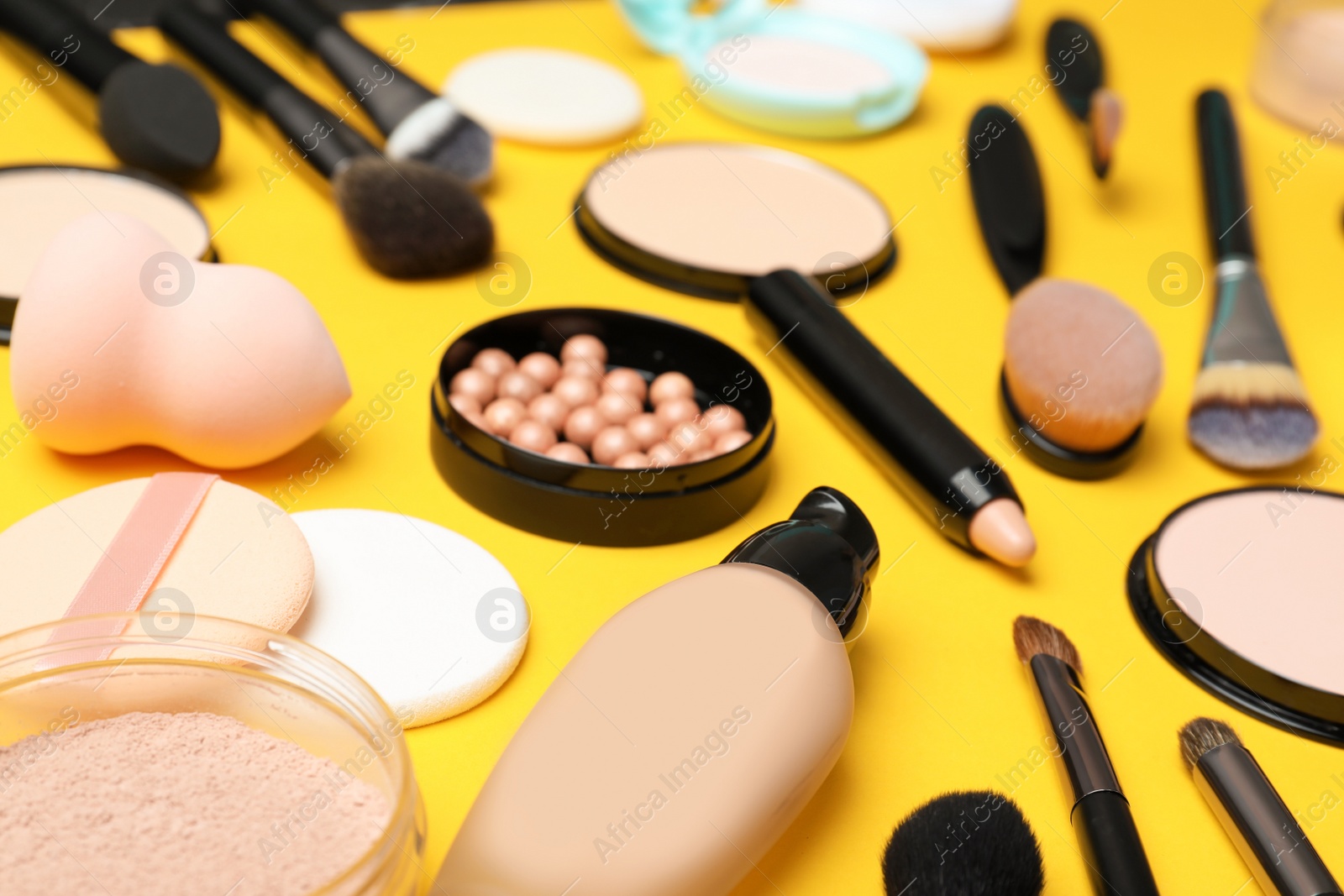 Photo of Composition with skin foundation, powder and beauty accessories on color background