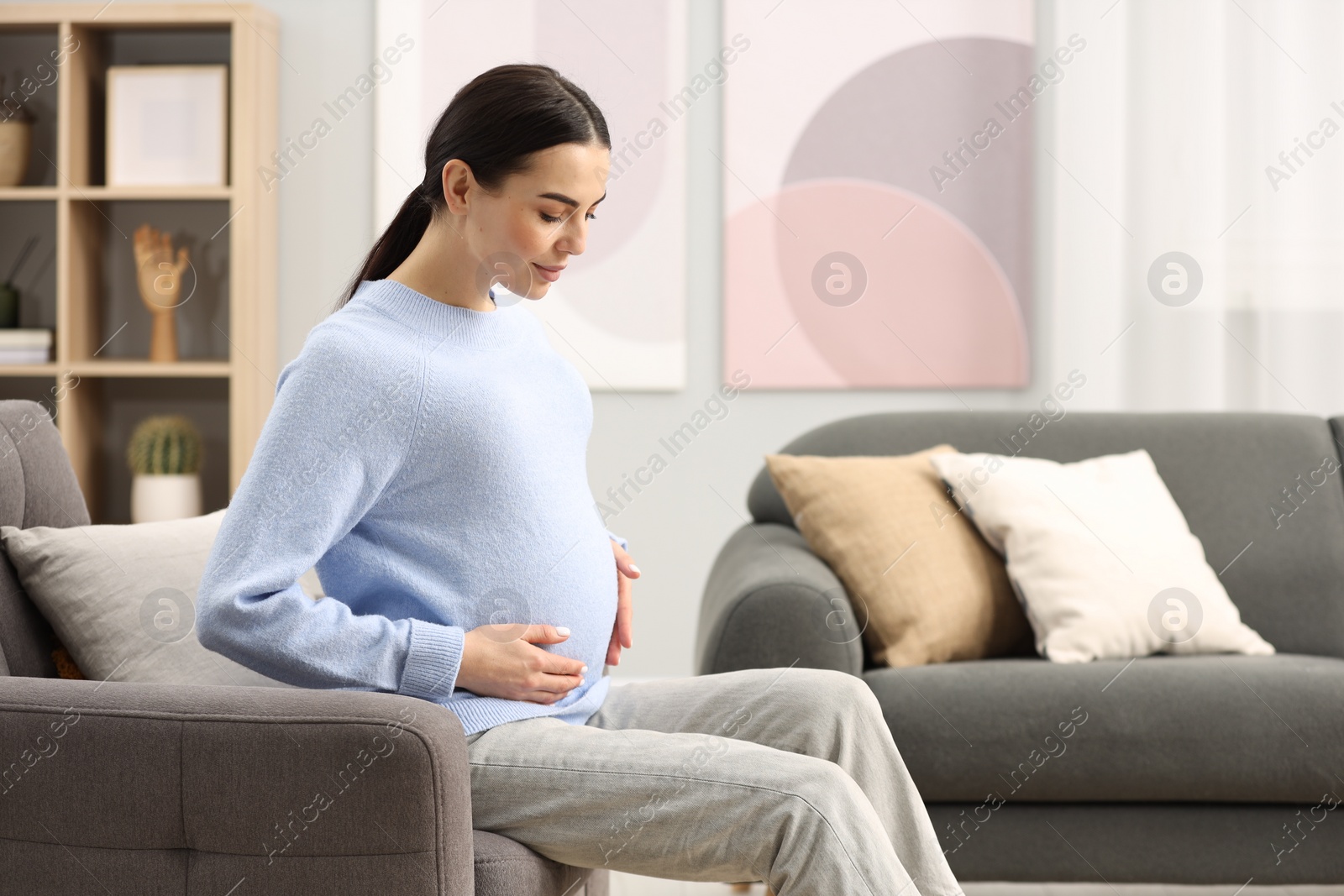 Photo of Pregnant young woman on armchair at home, space for text