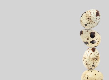 Image of Stacked speckled quail eggs on light grey background. Space for text