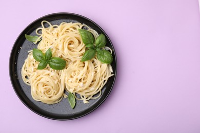 Delicious pasta with brie cheese and basil leaves on violet background, top view. Space for text