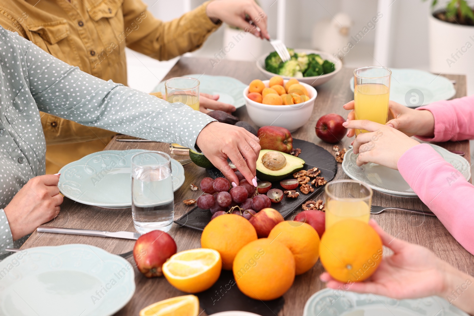 Photo of Friends eating vegetarian food at wooden table indoors, closeup