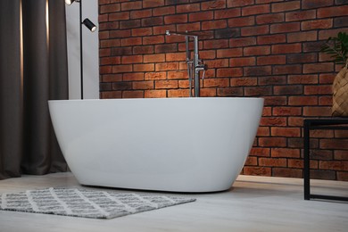 Stylish bathroom interior with ceramic tub and modern lamp