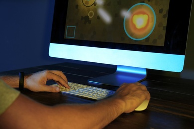 Photo of Man playing video game on modern computer in dark room, closeup