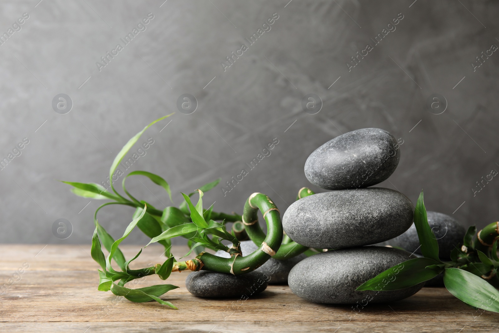 Photo of Stacked zen stones and bamboo on table against grey background. Space for text