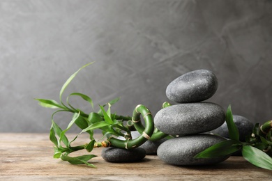 Photo of Stacked zen stones and bamboo on table against grey background. Space for text