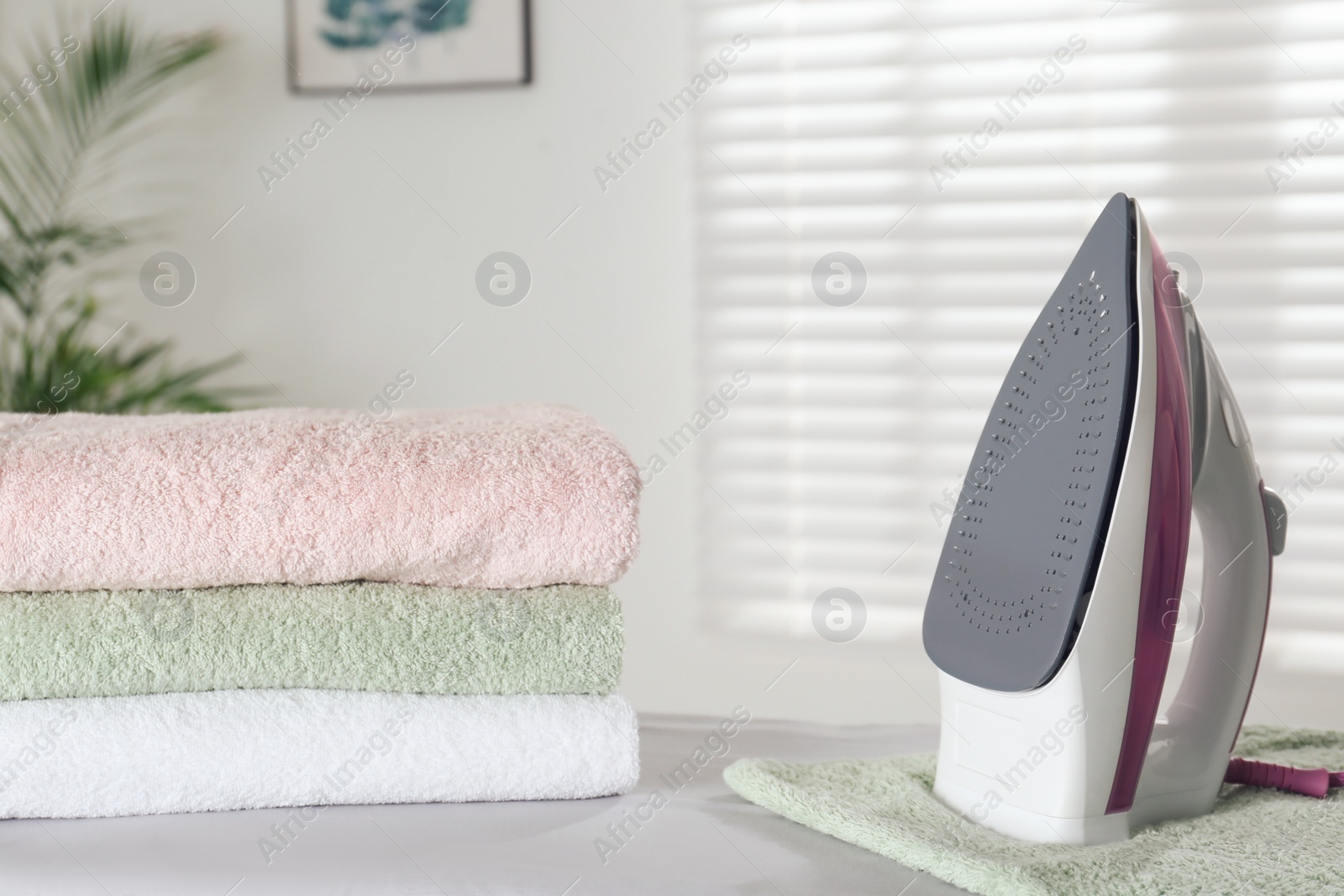 Photo of Modern iron and clean towels on board indoors