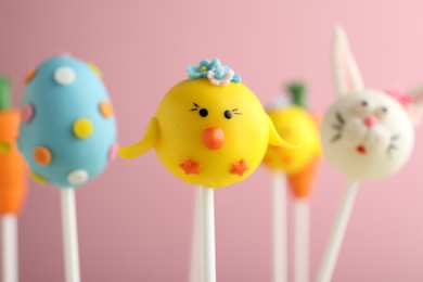 Photo of Delicious sweet cake pops on light pink background, closeup. Easter holiday