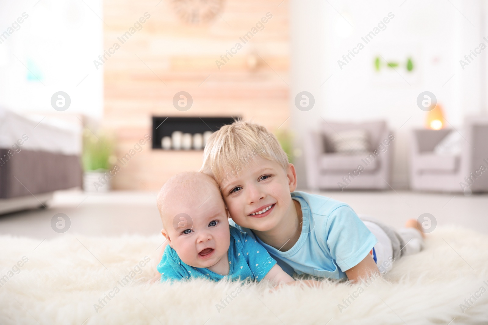 Photo of Cute boy with his little sister lying on fur rug at home