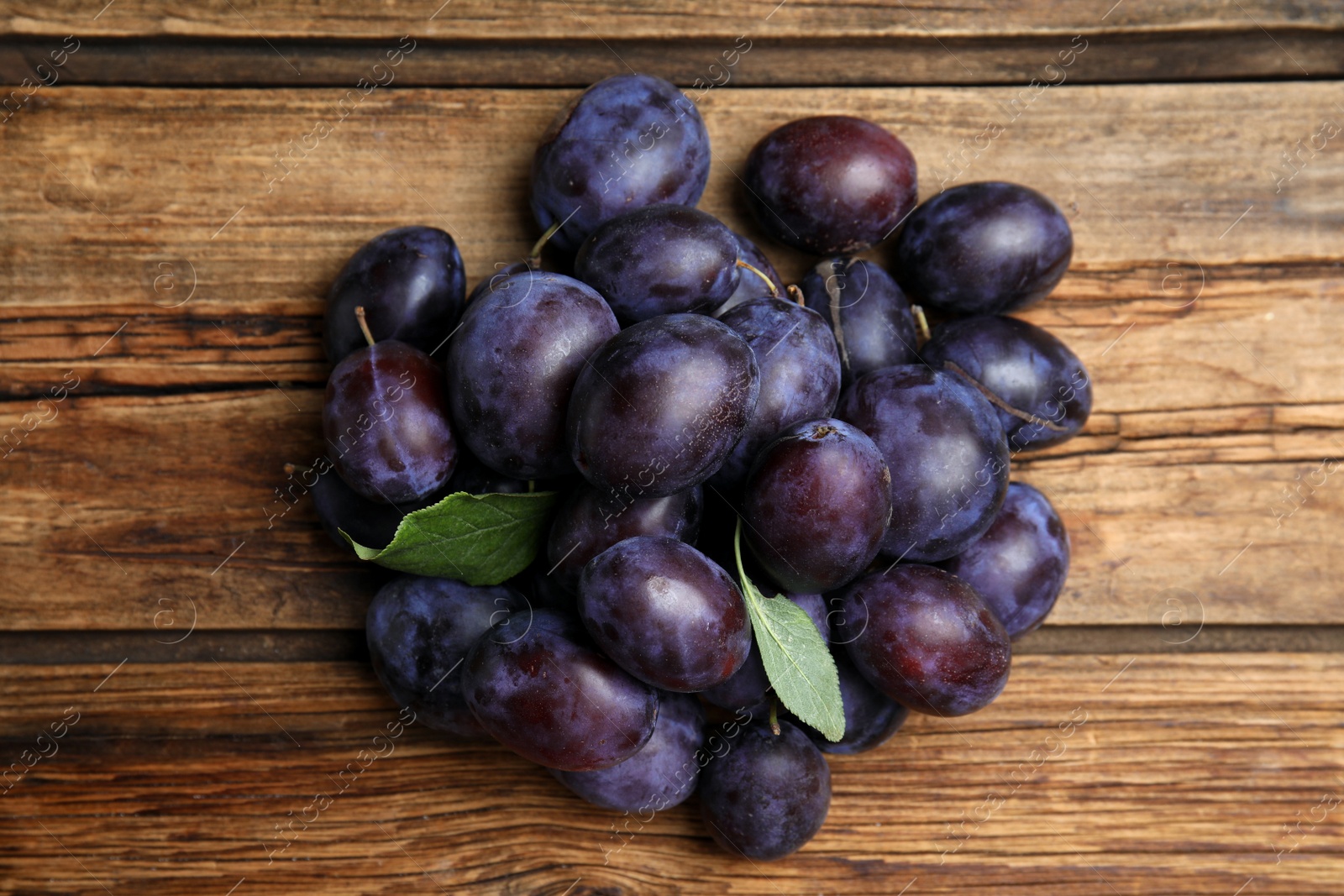 Photo of Delicious ripe plums on wooden table, flat lay