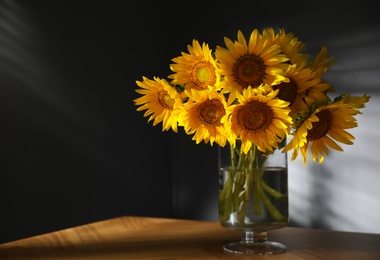 Photo of Bouquet of beautiful sunflowers in vase on table indoors. Space for text