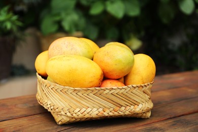 Photo of Delicious ripe juicy mangos on wooden table