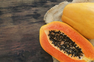 Photo of Tasty cut and whole papaya fruits on wooden table, top view. Space for text