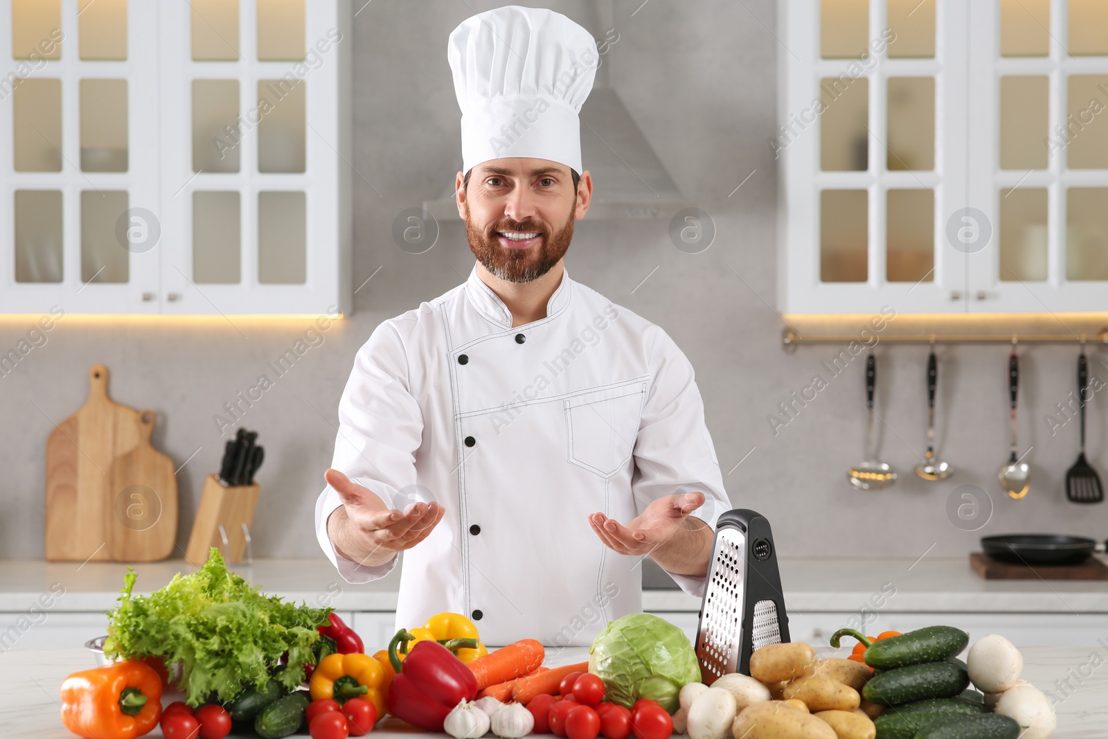 Photo of Portrait of happy professional chef near vegetables at marble table in kitchen