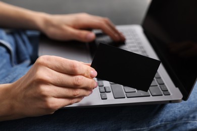 Woman with laptop holding blank business card, closeup. Space for text