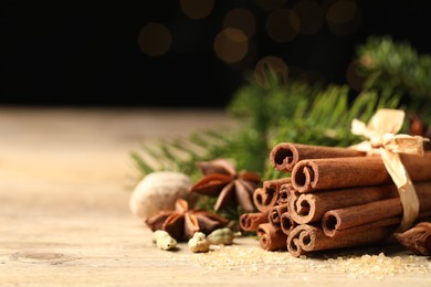 Different aromatic spices on wooden table against black background, closeup. Space for text