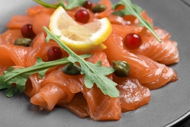 Photo of Salmon carpaccio with capers, cranberries, arugula and lemon on plate, closeup