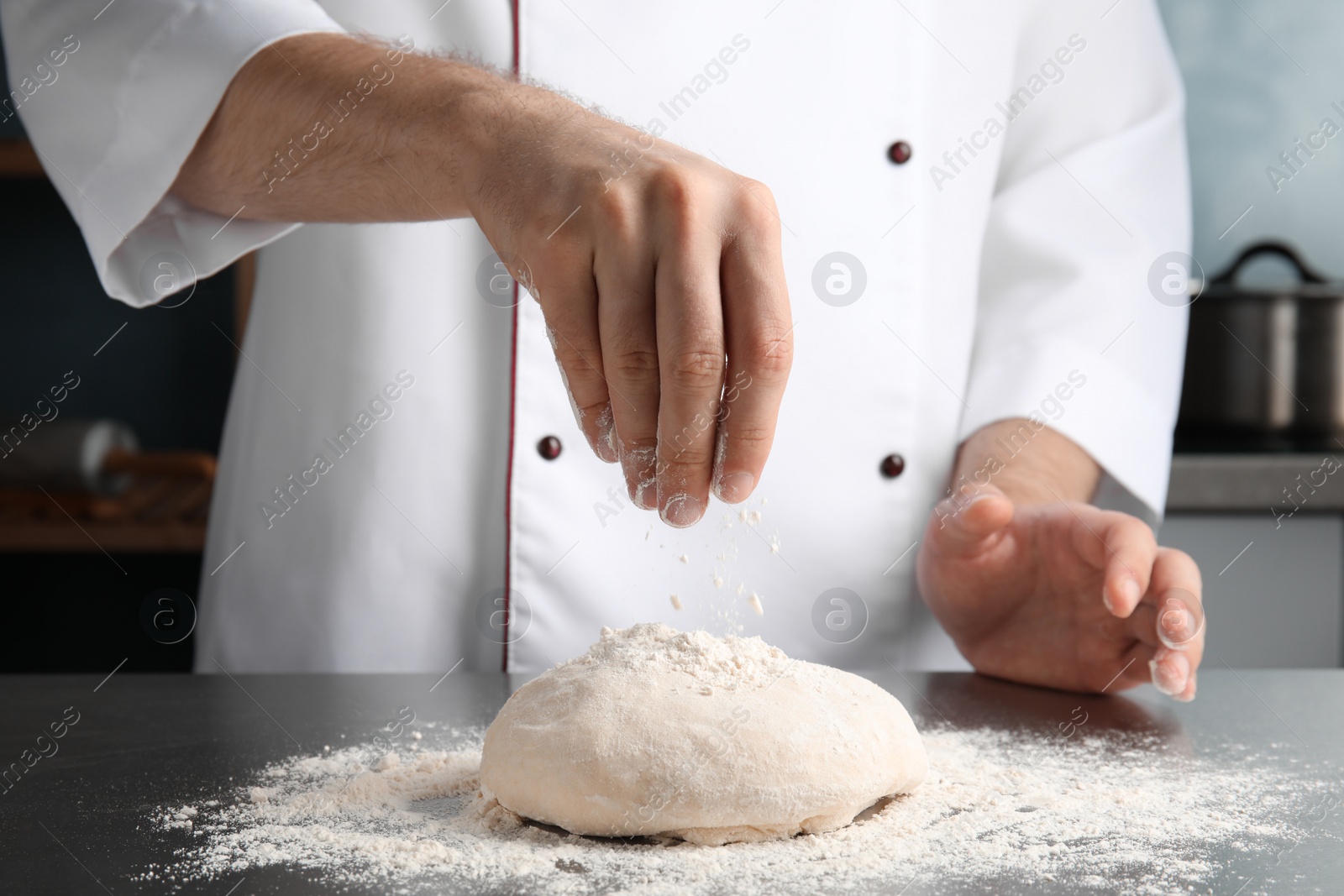 Photo of Man sprinkling dough for pastry with flour on table