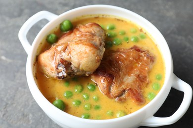 Tasty cooked rabbit meat with sauce and peas on grey table, closeup