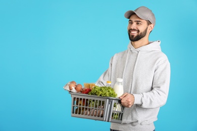 Photo of Man holding basket with fresh products on color background, space for text. Food delivery service