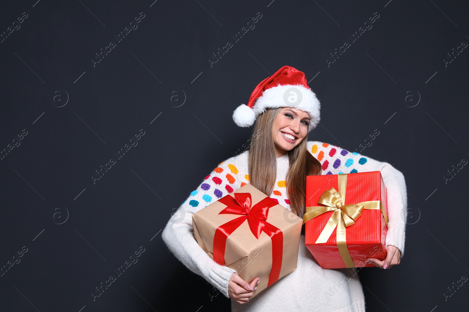 Photo of Young woman with Christmas gifts on dark background. Space for text