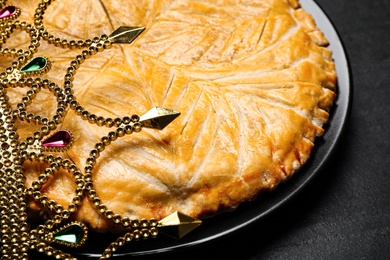 Traditional galette des rois with crown on black table, closeup