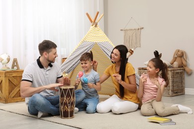 Happy family playing together near toy wigwam at home