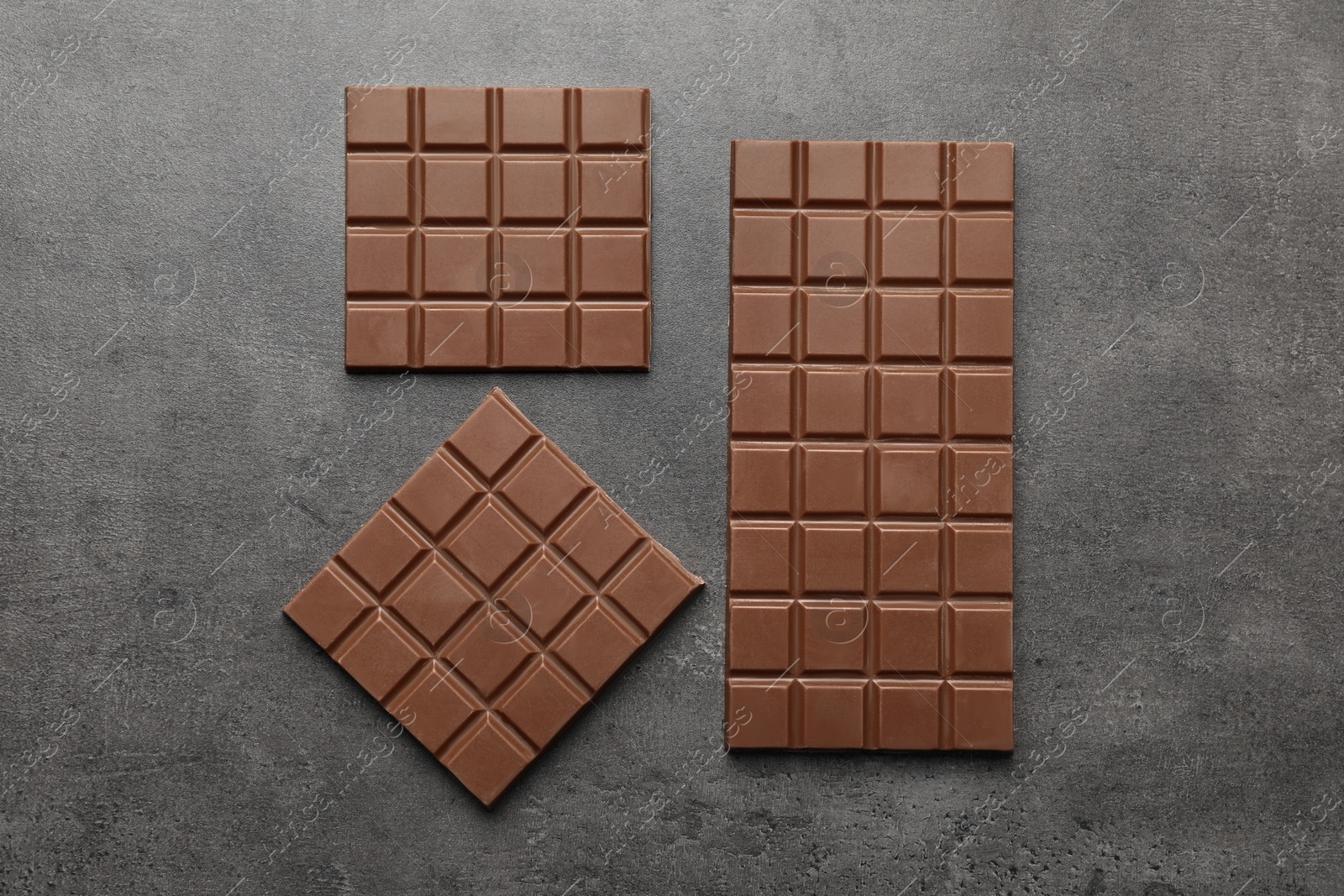 Photo of Delicious milk chocolate bars on grey table, flat lay