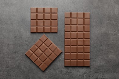 Delicious milk chocolate bars on grey table, flat lay