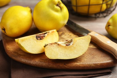 Photo of Ripe whole and cut quinces with knife on table, closeup