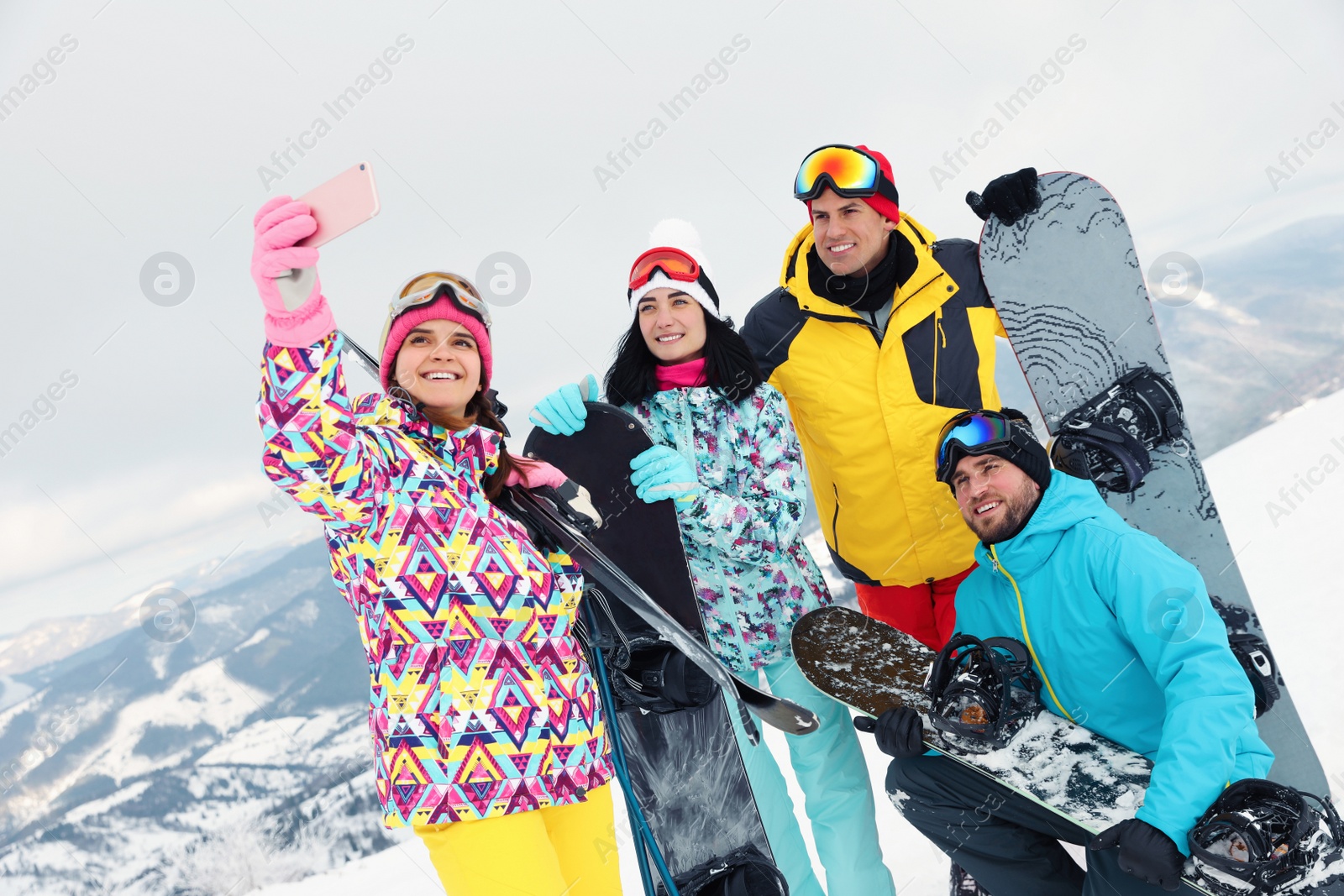 Photo of Group of friends taking selfie in snowy mountains. Winter vacation