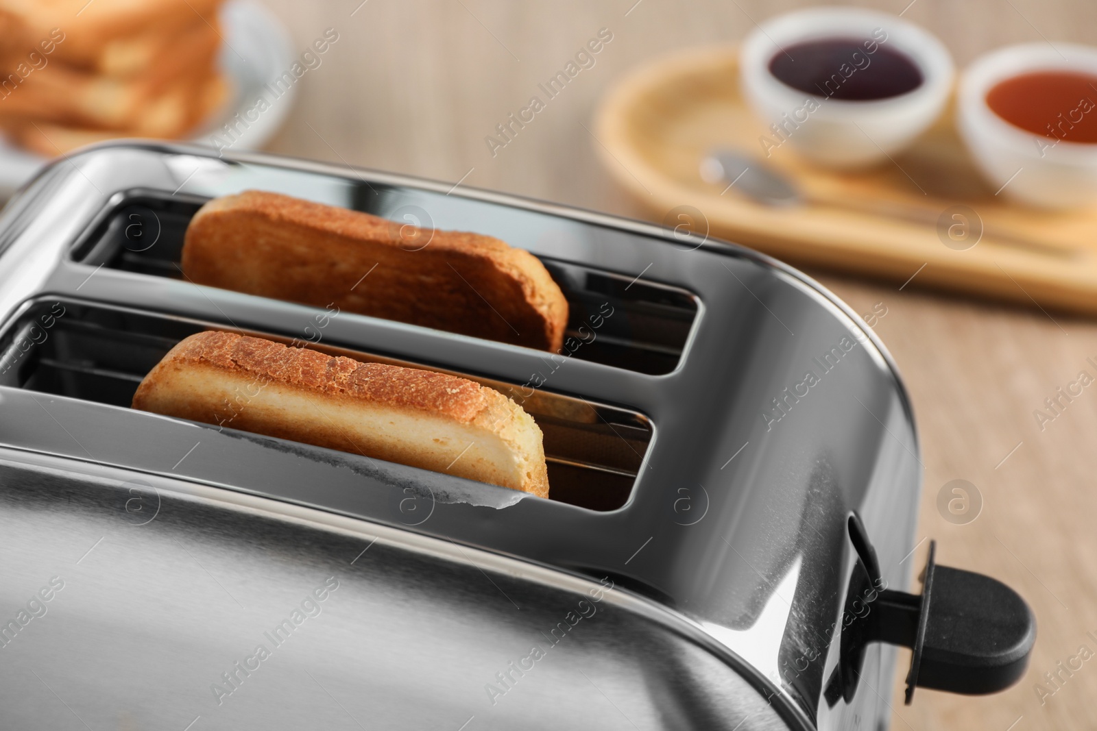 Photo of Closeup view of toaster with roasted bread on wooden table