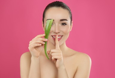 Photo of Young woman with aloe vera leaf on pink background