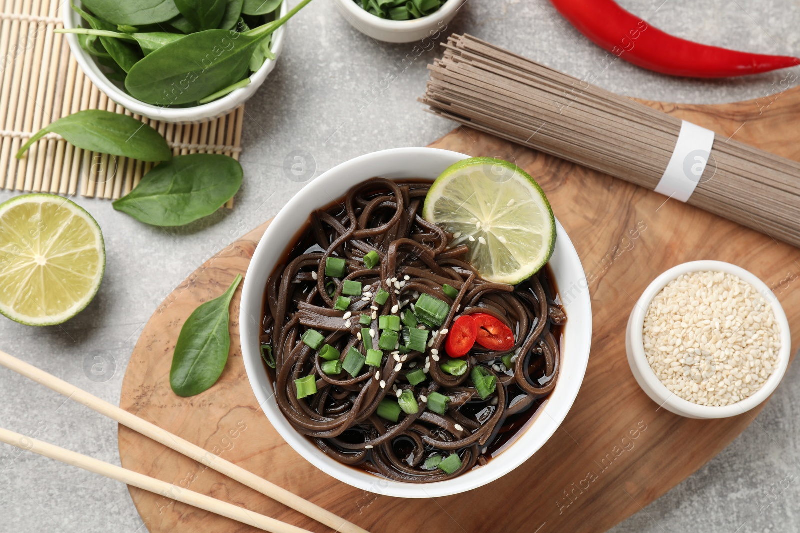 Photo of Tasty buckwheat noodles (soba) served on light grey table, flat lay