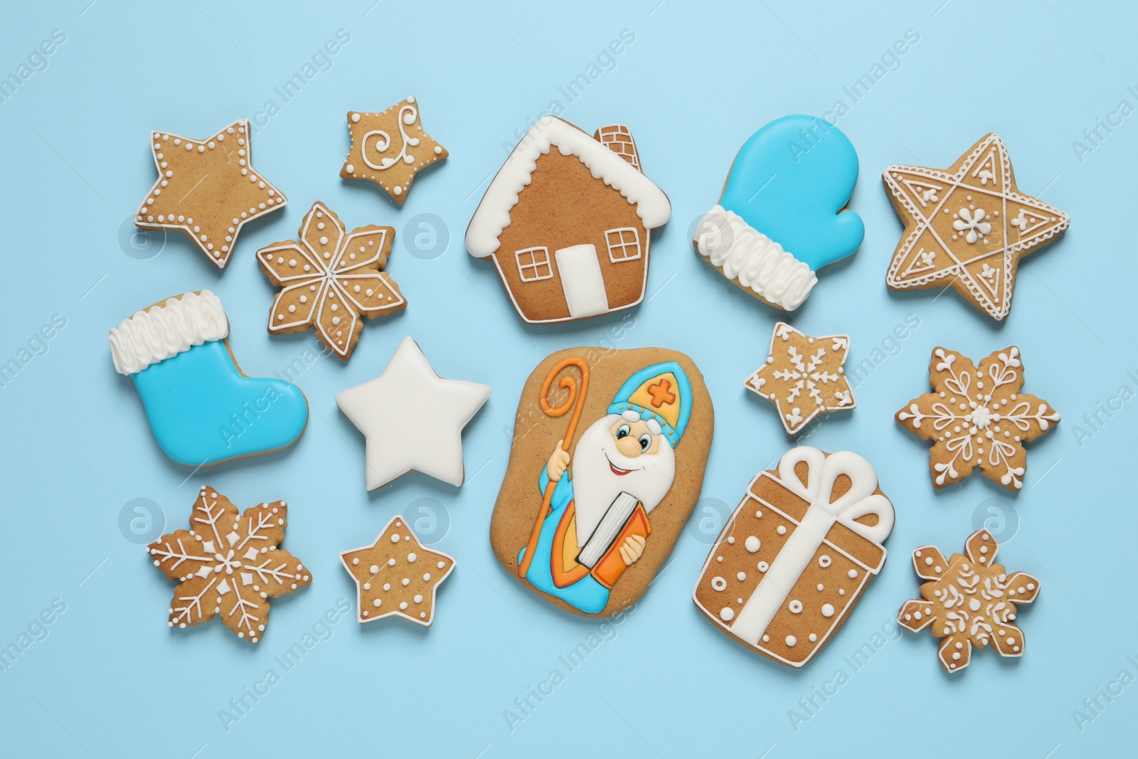 Photo of Tasty gingerbread cookies on light blue background, flat lay. St. Nicholas Day celebration