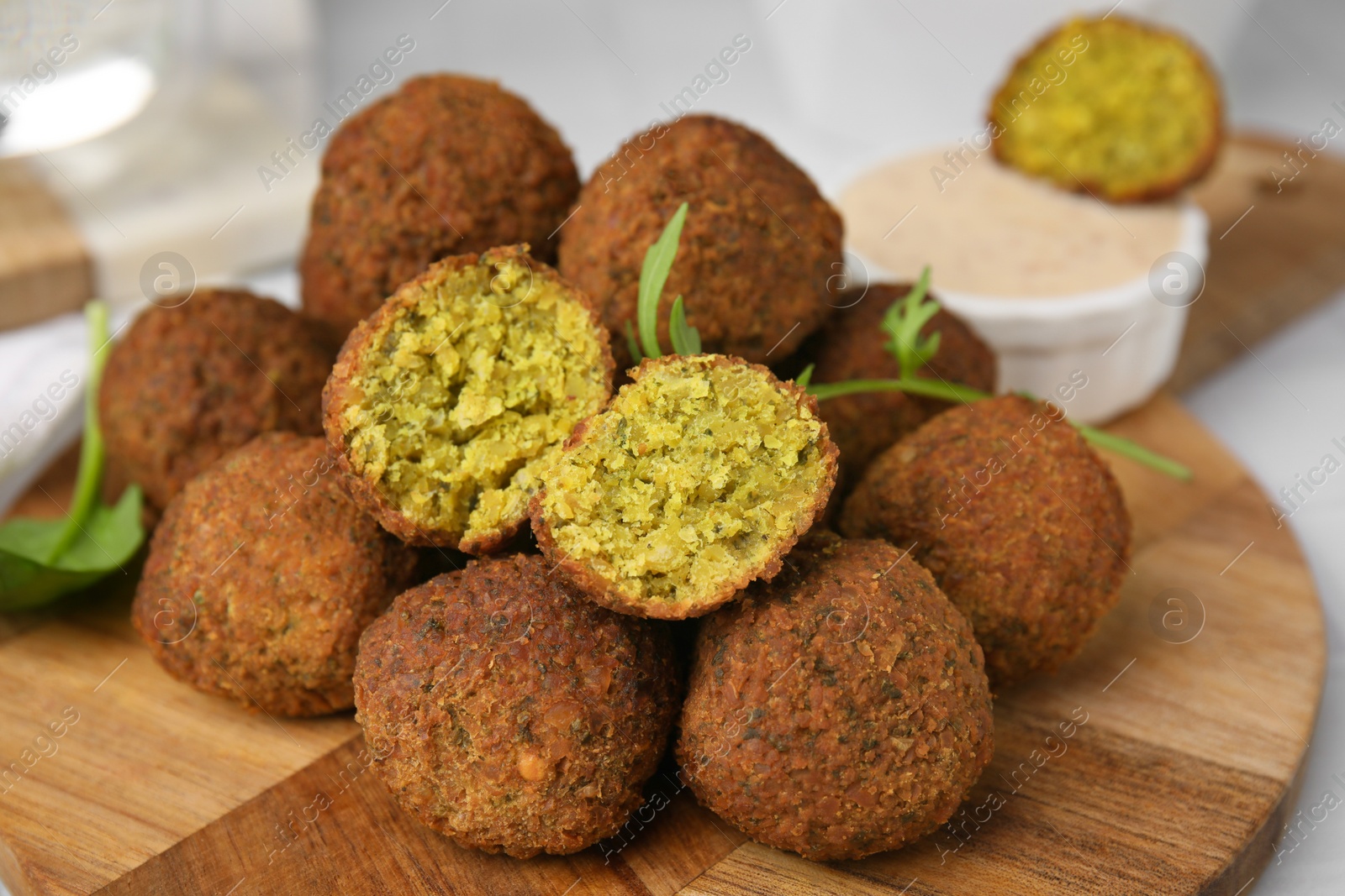 Photo of Delicious falafel balls, herbs and sauce on table, closeup