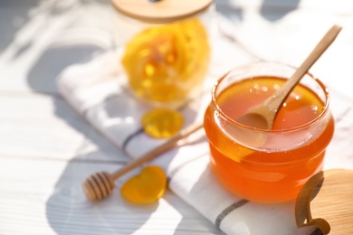 Composition with glass jar of fresh rose honey on white wooden table. Space for text