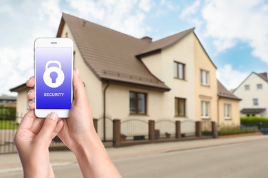 Image of Home security system. Woman with smartphone near her house outdoors, closeup