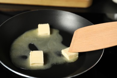 Photo of Stirring melting butter in frying pan on table, closeup