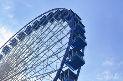 Amusement park. Beautiful Ferris wheel against blue sky, low angle view