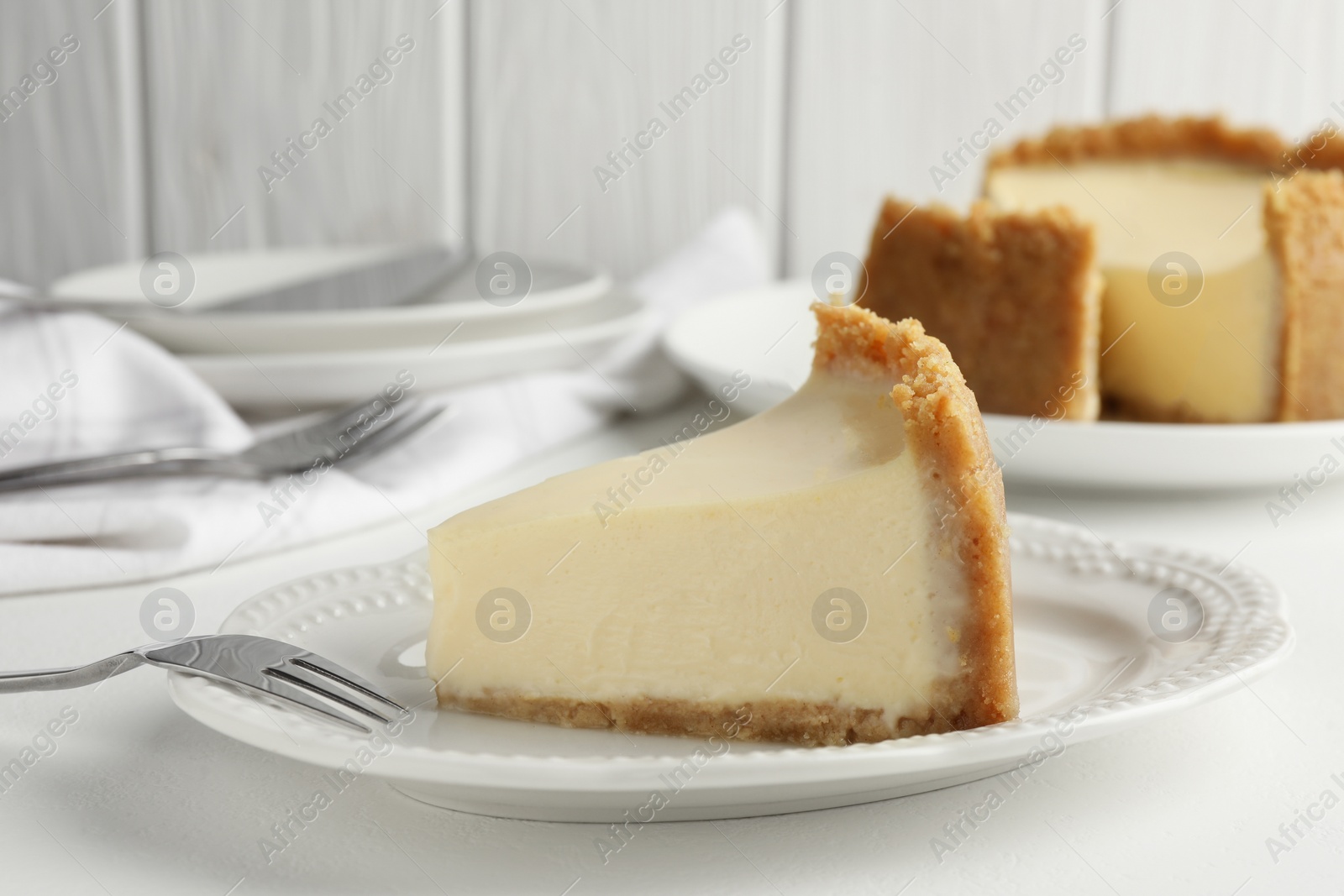 Photo of Piece of tasty vegan tofu cheesecake and fork on white table, closeup