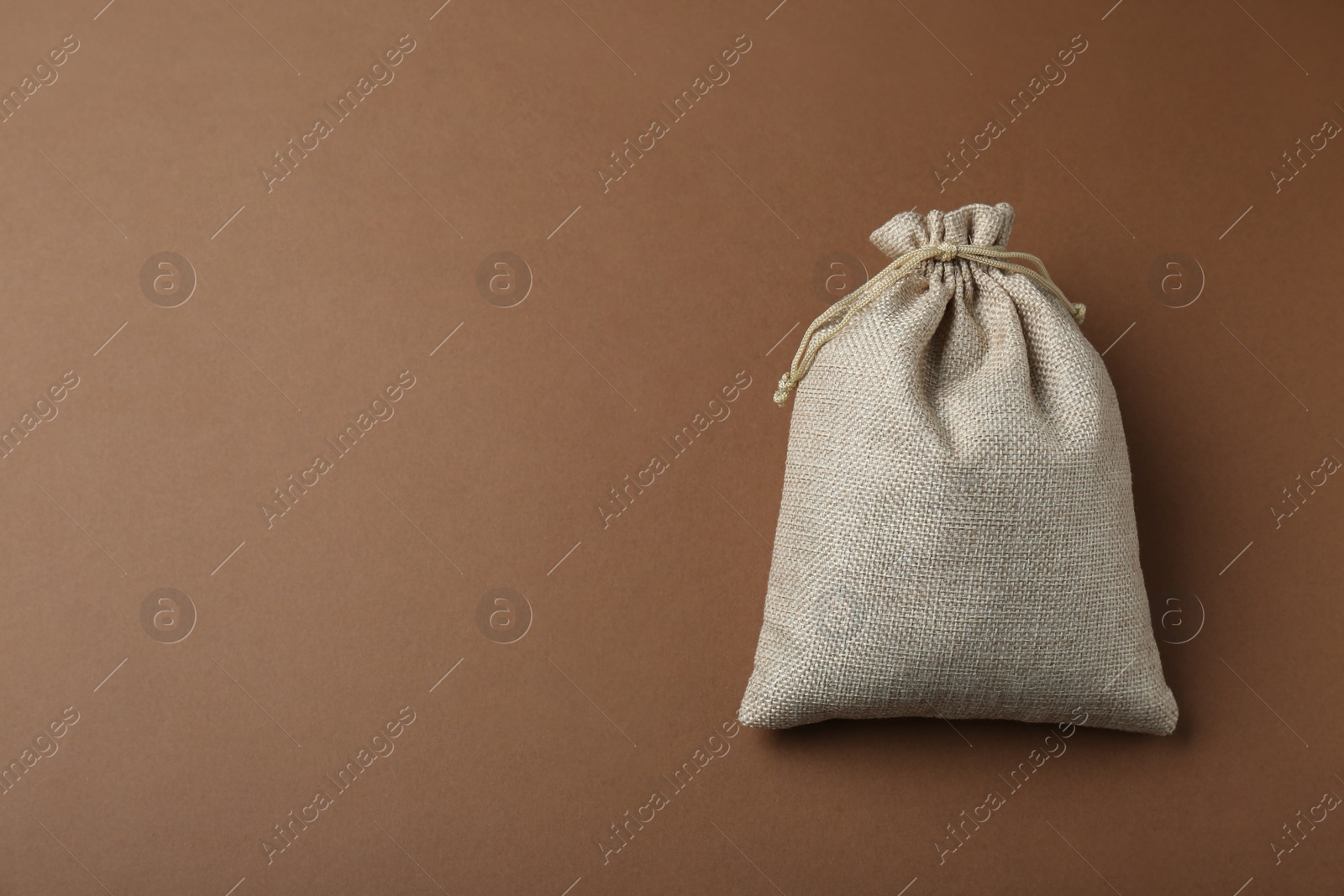 Photo of Burlap bag on brown background, top view. Space for text