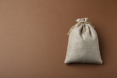 Photo of Burlap bag on brown background, top view. Space for text